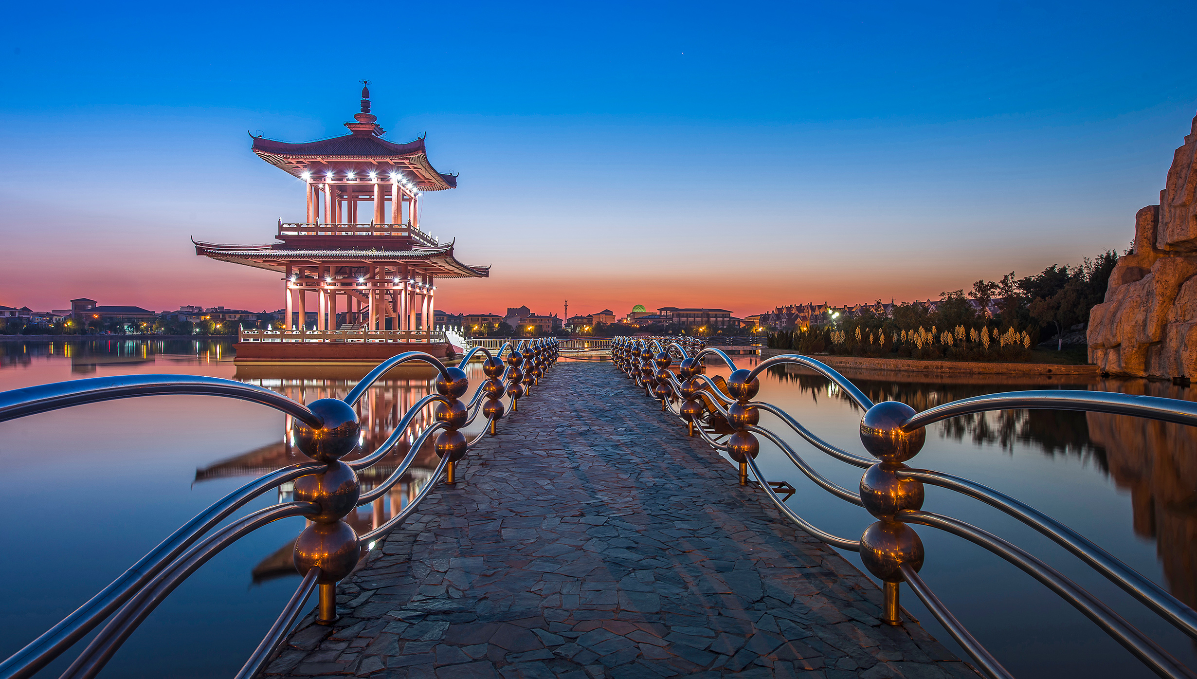 A traditional Chinese pavilion on a serene lake at sunset | MSC Cruises