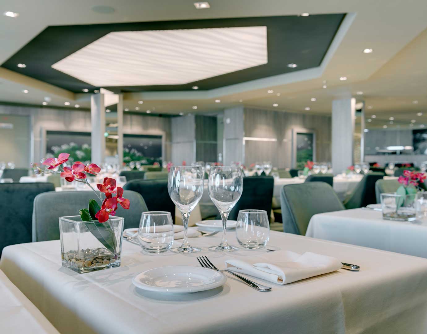 Elegant dining room with neatly set tables and floral centerpieces on an MSC cruise ship | MSC Cruises