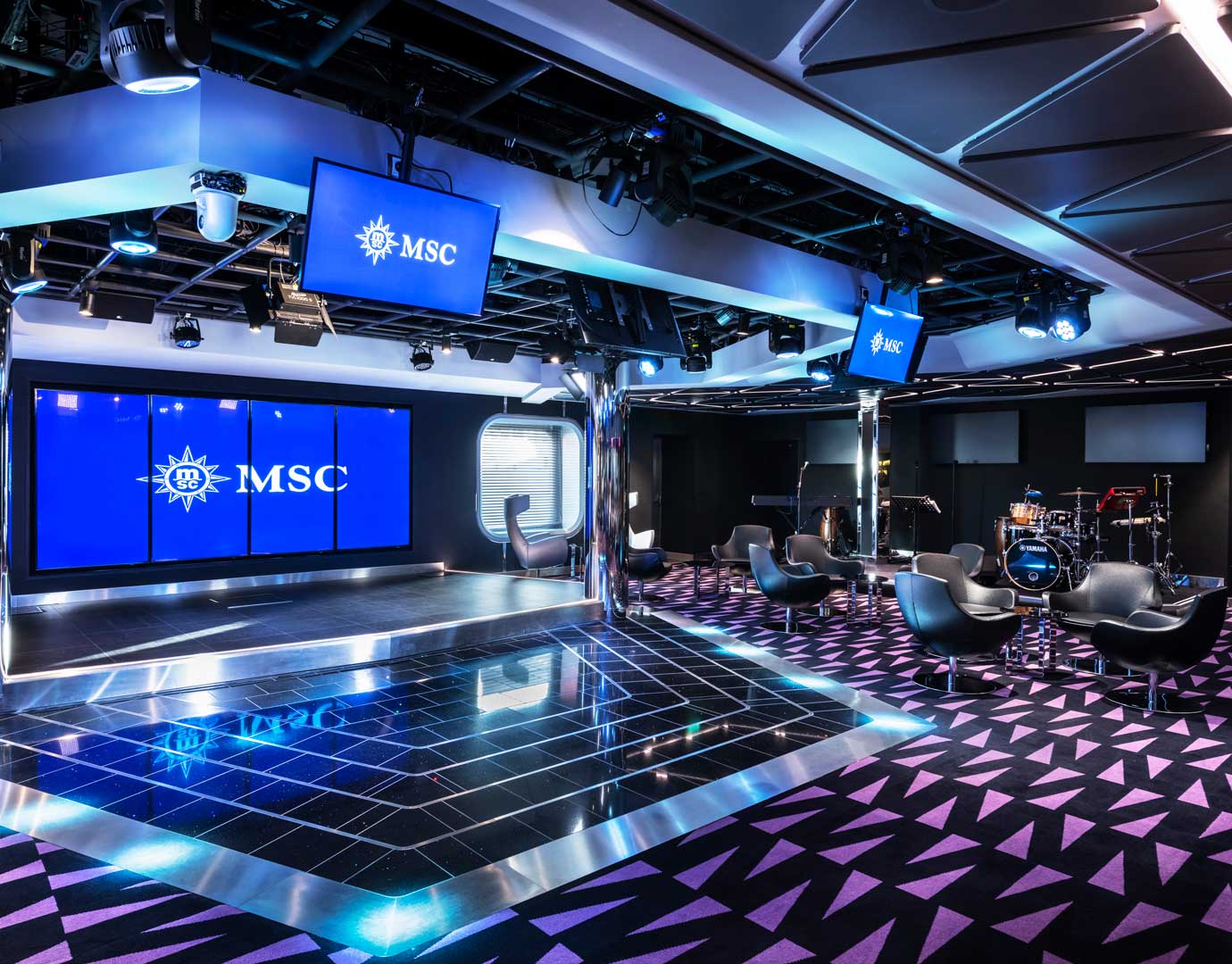 A modern entertainment lounge with stage, instruments, and MSC branding | MSC Cruises